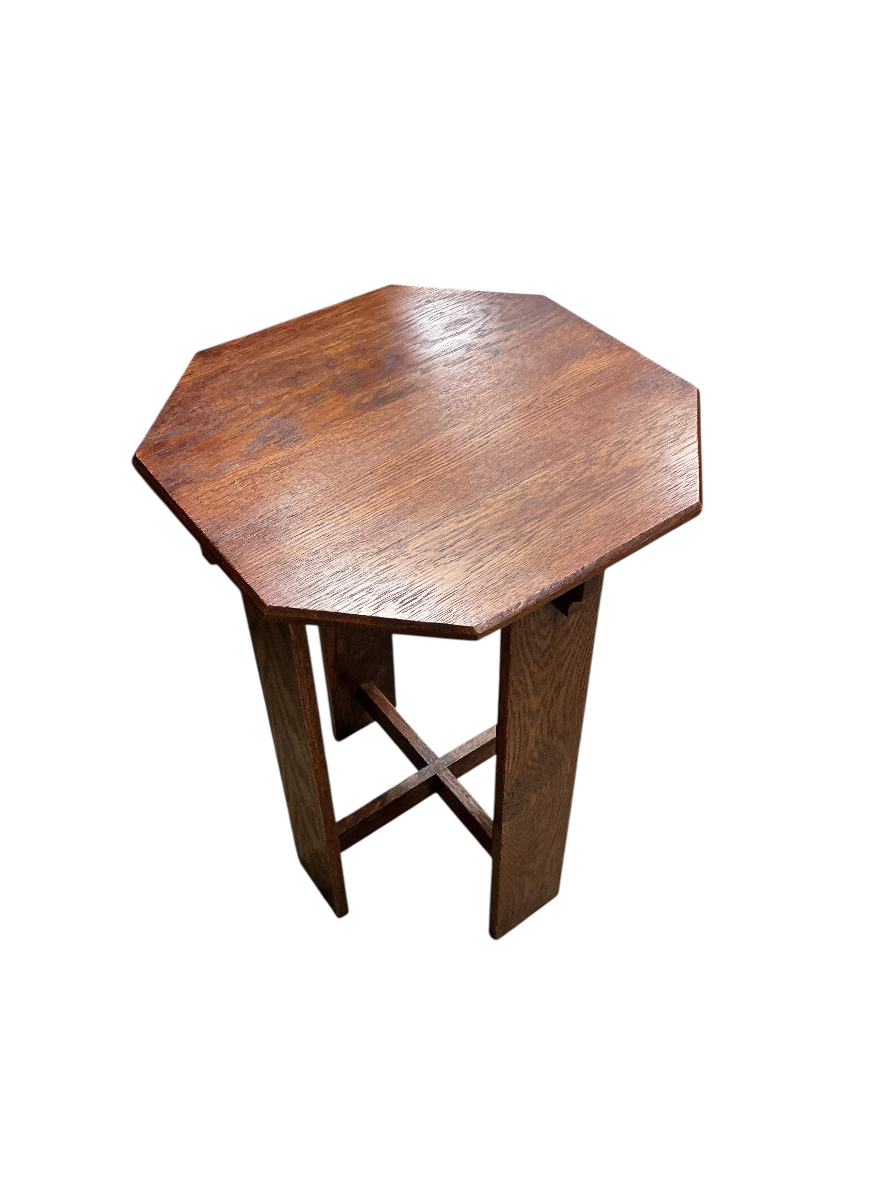 A pair of Liberty style Arts and Crafts oak reclining armchairs and an oak octagonal occasional table